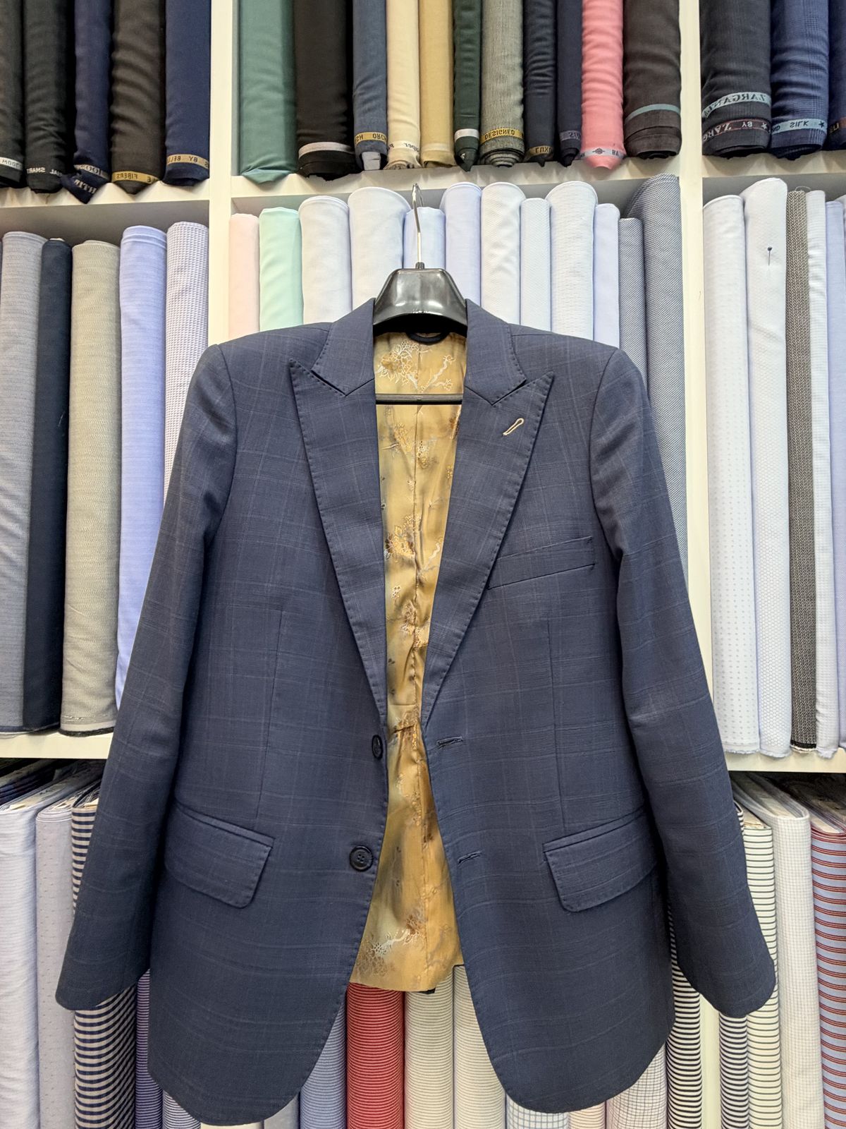 Navy check jacket on a hanger, open to show a gold lining