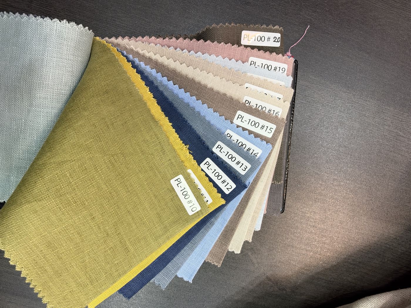 A fan of linen swatches in olive, pink, blue, sand and grey