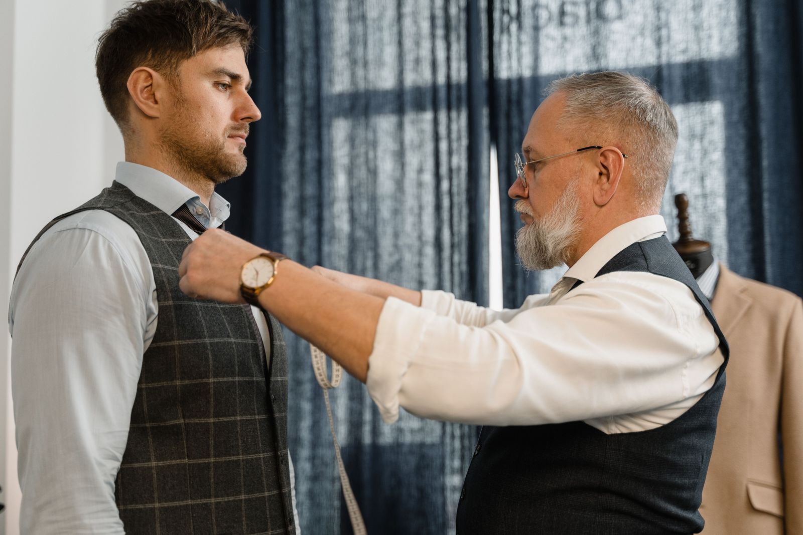 A tailor measuring a customer’s chest with a tape measure