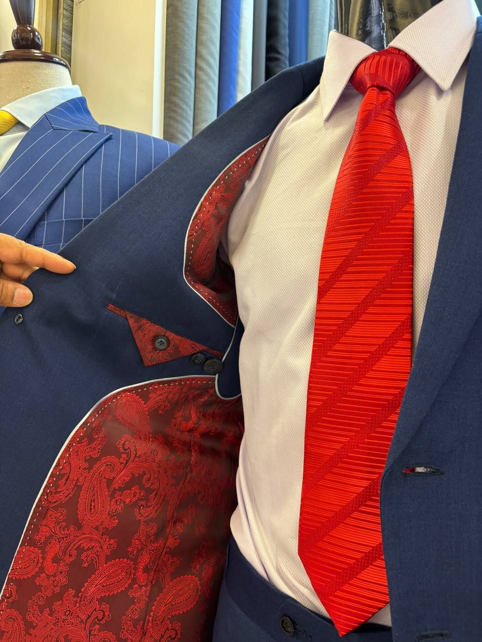 Navy suit held open to show a red paisley lining, worn with a red tie