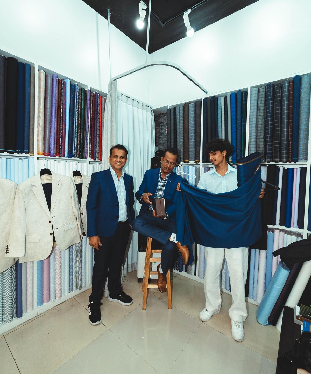 The shop’s fabric room with staff holding up a length of navy cloth